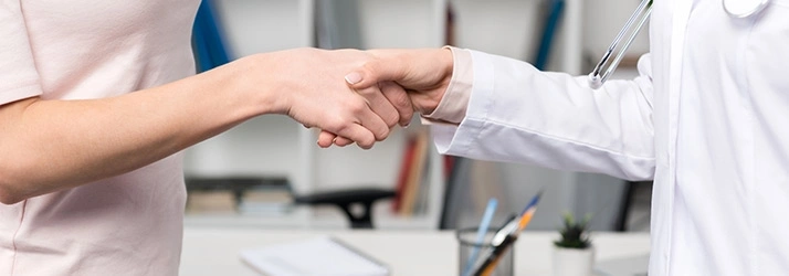 Close-up of a handshake between a patient and a healthcare provider