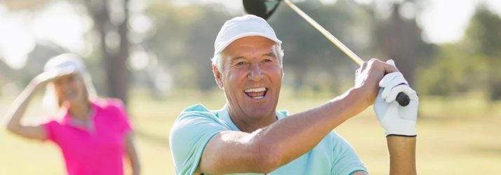 Person wearing a golf glove and cap swinging a golf club