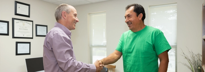 Dr. Scott Lally welcoming a new patient and discussing their health history during a first visit consultation at Lally Chiropractic Clinic in Yakima, WA.